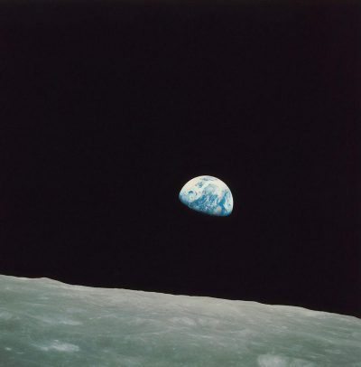 The earthrise photo taken from the Apollo space mission, showing half of planet Earth and black sky above it. The scene is captured in color with high resolution and a sense of awe-inspiring scale, showcasing both the tranquility and grandeur of our home world in the style of the artist.