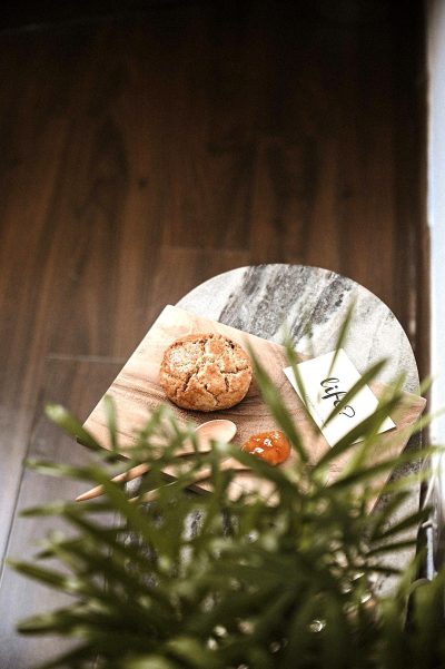 A photo of an abstract round wooden and marble board with bread, plants and some cards on it taken from above, wooden floor in the background, shot in the style of using a leica lens for his first mastercraft photography collection, cinematic lighting, hyper realistic.